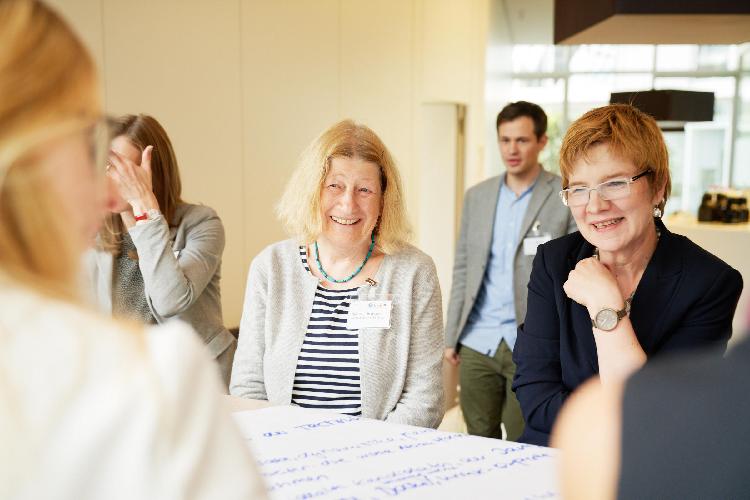 Prof. Dr. Britta Schinzel und Prof. Dr. Nicola Marsden sitzen in einem Workshop zusammen mit anderen Teilnehmenden an einem Plakat.